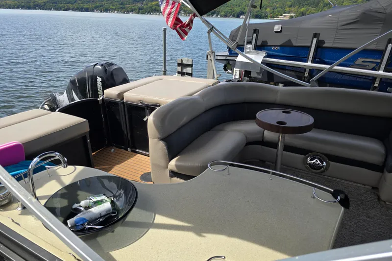 Slide: The Image of 2013 Premier 275 Boundary Waters pontoon boat interior with seating and table on a lake. - 9