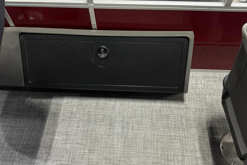 Slide: The Image of 2026 Sun Tracker SportFish 22 DLX interior storage compartment with lock on gray carpet. - 31