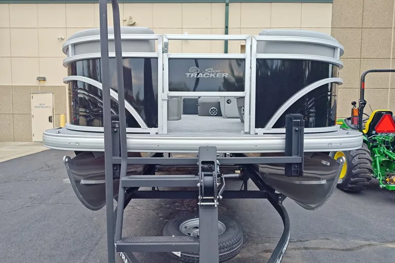 Slide: The Image of 2026 Sun Tracker SportFish 22 DLX pontoon boat on trailer, parked outdoors. - 2