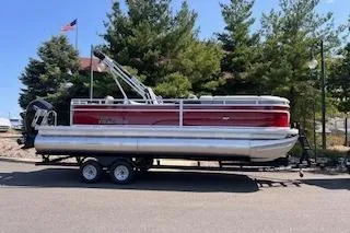 The Image of 2026 Sun Tracker SportFish 22 DLX pontoon boat on trailer, parked outdoors. - 0