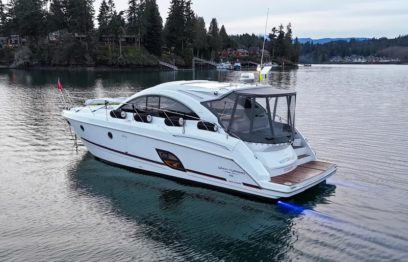 The Image of 2015 Beneteau Gran Turismo 44 yacht cruising on a serene lake with forested shoreline. - 1
