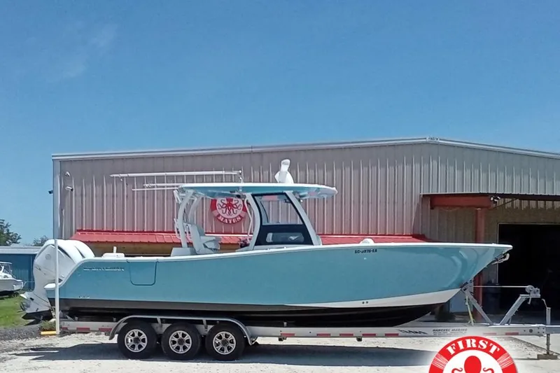 The Image of 2022 Sportsman Open 302 Center Console boat on trailer, parked outside a warehouse. - 1