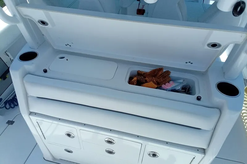 Slide: The Image of 2022 Sportsman Open 302 Center Console boat storage compartment with open lid and cup holders. - 23