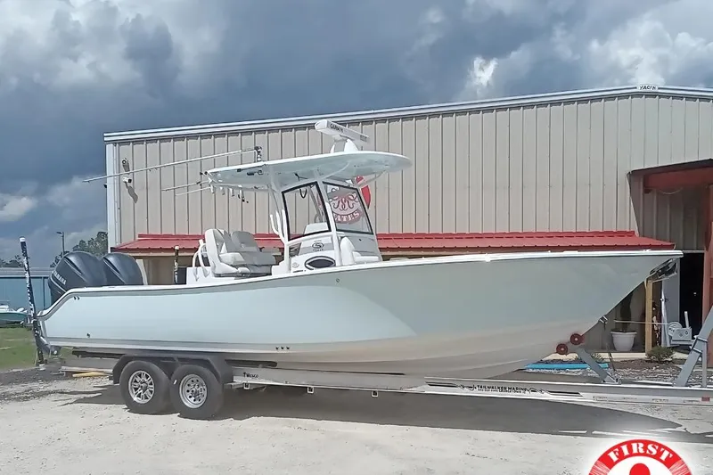 The Image of 2020 Sportsman Open 282TE Center Console boat on trailer, parked outside a building. - 1