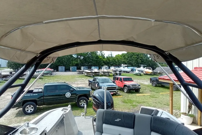 Slide: The Image of 2019 Starcraft MX 23 C boat interior with canopy, parked vehicles, and boats in the background. - 14