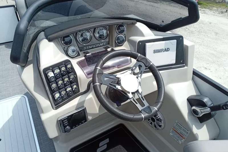 Slide: The Image of 2019 Starcraft MX 23 C boat dashboard with steering wheel, gauges, and Simrad display. - 15