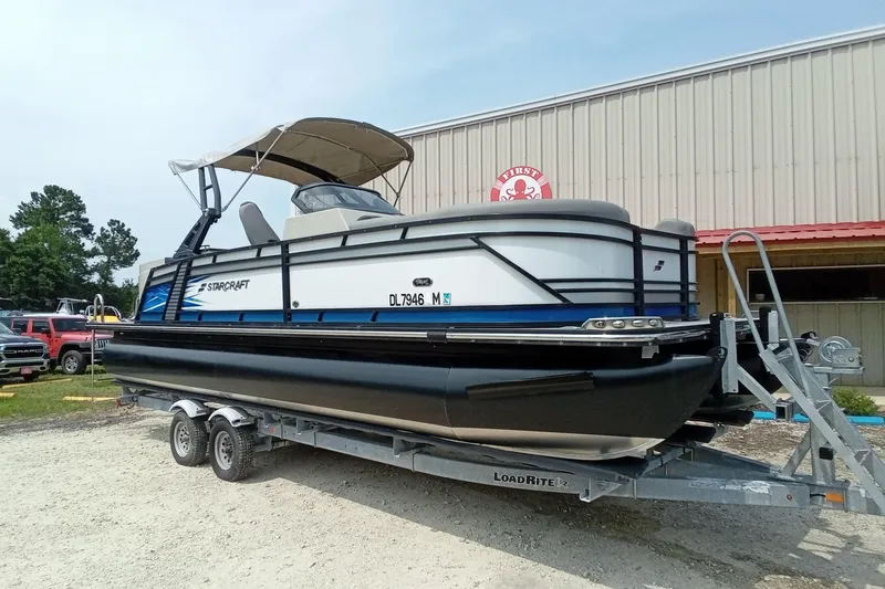 Slide: The Image of 2019 Starcraft MX 23 C pontoon boat on trailer, parked outside a building. - 26