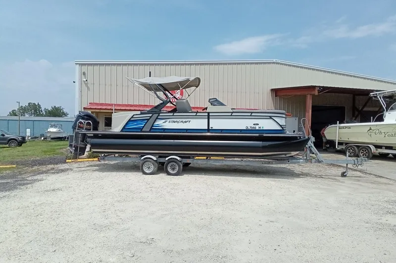Slide: The Image of 2019 Starcraft MX 23 C pontoon boat on trailer outside storage facility. - 27
