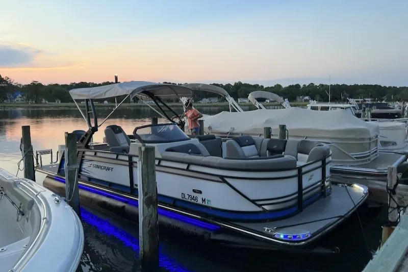 Slide: The Image of 2019 Starcraft MX 23 C pontoon boat docked at sunset with blue LED lights. - 3