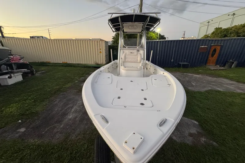 Slide: The Image of 2016 Sea Hunt BX 22 boat with T-top, parked on grass near shipping containers. - 10