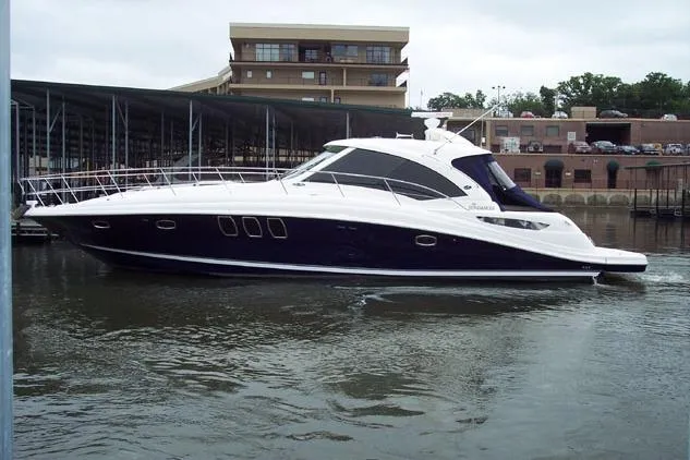 The Image of 2005 Sea Ray 48 Sundancer yacht on a calm lake with scenic background. - 0