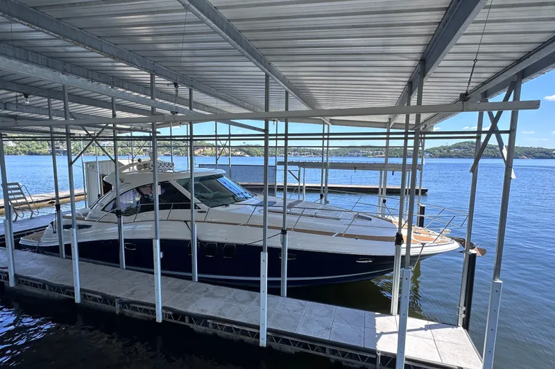 Slide: The Image of 2005 Sea Ray 48 Sundancer yacht cruising on a serene lake under a clear blue sky. - 2