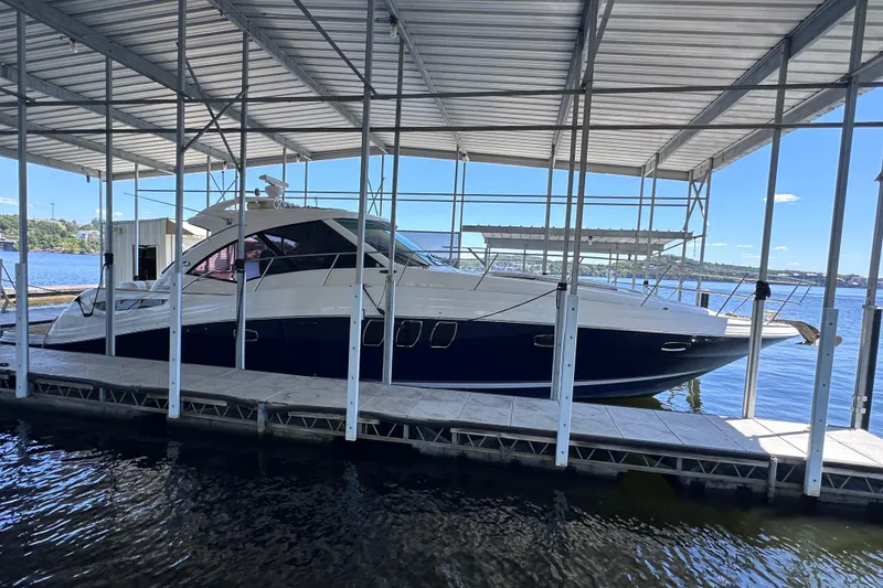 Slide: The Image of 2005 Sea Ray 48 Sundancer yacht cruising on a serene lake under a clear blue sky. - 4