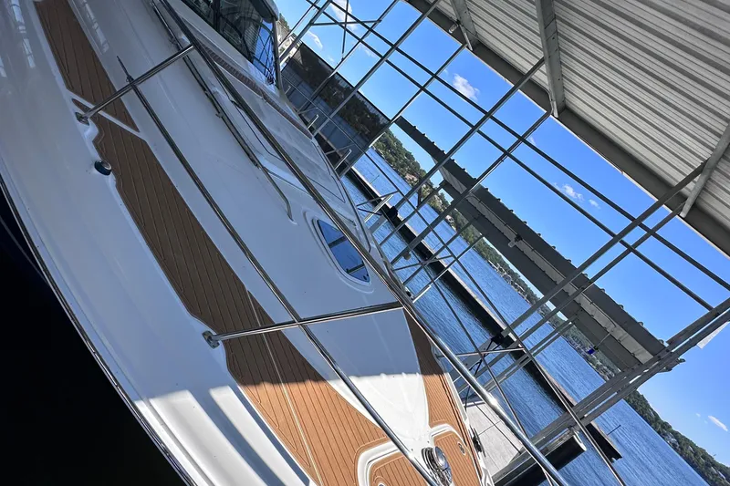 Slide: The Image of 2005 Sea Ray 48 Sundancer yacht cruising on a serene lake under clear blue skies. - 6