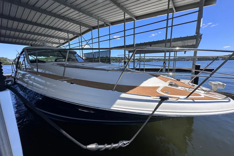 Slide: The Image of 2005 Sea Ray 48 Sundancer yacht cruising on a serene lake with wooded shoreline. - 8