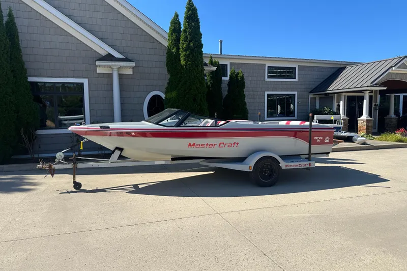The Image of 1987 MasterCraft ProStar 190 boat on trailer, parked outside a building. - 0