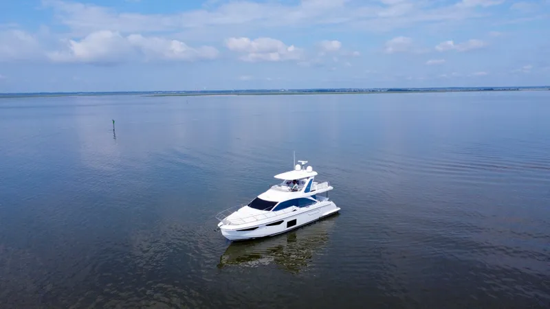 Slide: The Image of 2022 Azimut Fly 60 yacht cruising on calm waters under a blue sky. - 25