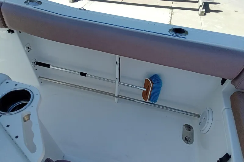 Slide: The Image of 2019 Sea Hunt Ultra 255 SE boat interior with storage and cleaning brush. - 14