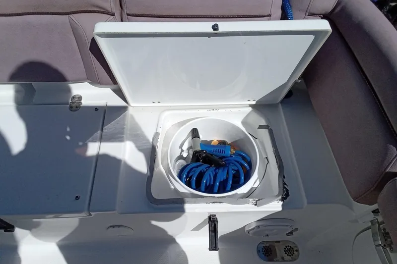 Slide: The Image of Storage compartment on a 2019 Sea Hunt Ultra 255 SE boat with coiled hose. - 42