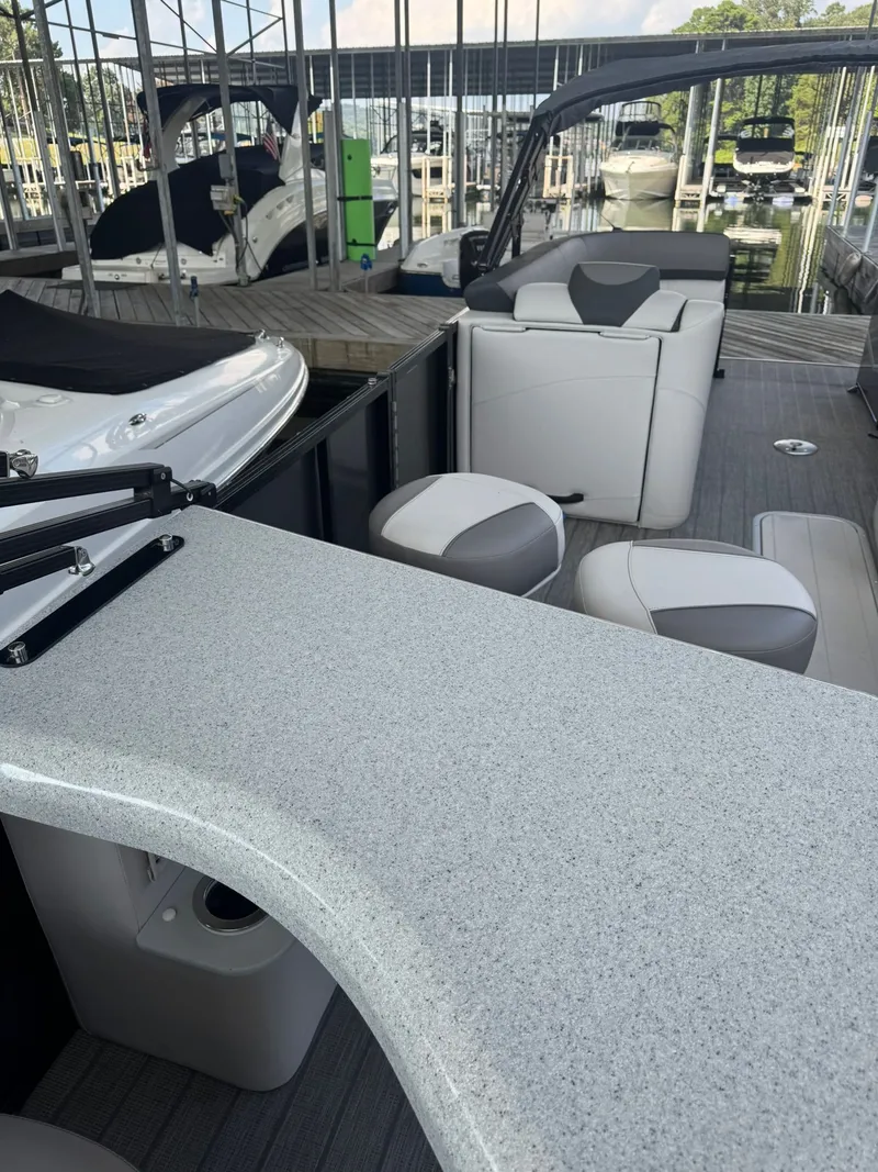 Slide: The Image of 2021 Avalon LSZ 2485 Ent pontoon boat interior with seating and countertop in marina. - 2