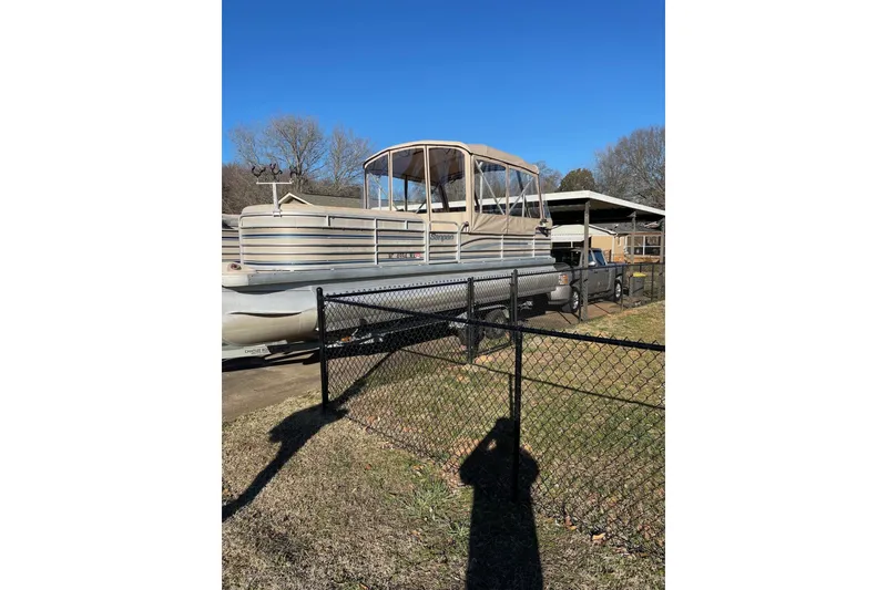 Slide: The Image of 2003 Godfrey SANPAN 2500 pontoon boat parked behind a black fence. - 32