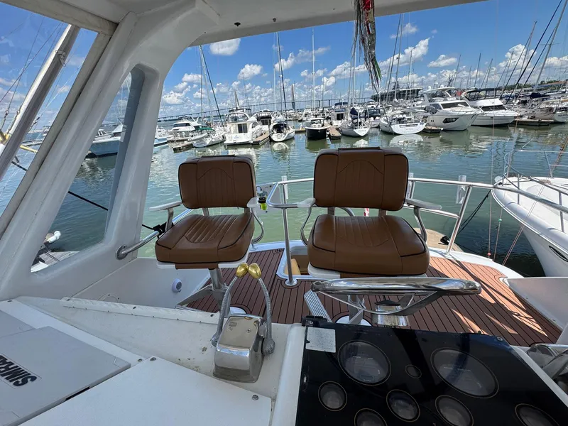 Slide: The Image of 1998 Ocean Yachts 40 Super Sport cockpit with marina view, featuring two brown captain chairs. - 22