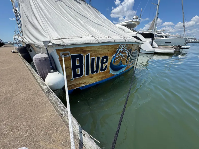 Slide: The Image of 1998 Ocean Yachts 40 Super Sport docked, featuring "Blue" on the stern, covered with a tarp. - 8