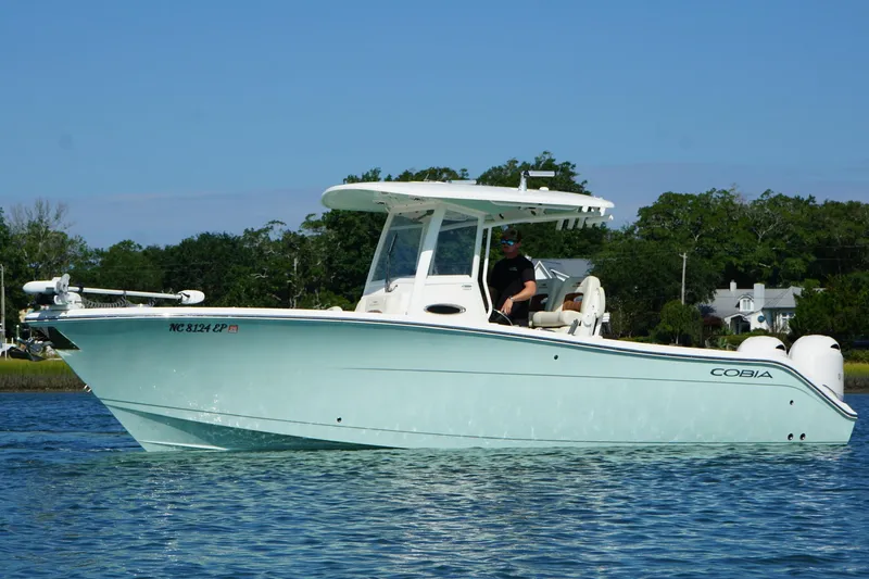 The Image of 2020 Cobia 280 Center Console boat on calm water, with trees in the background. - 0
