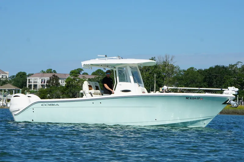 Slide: The Image of 2020 Cobia 280 Center Console boat on water, with trees and buildings in the background. - 1
