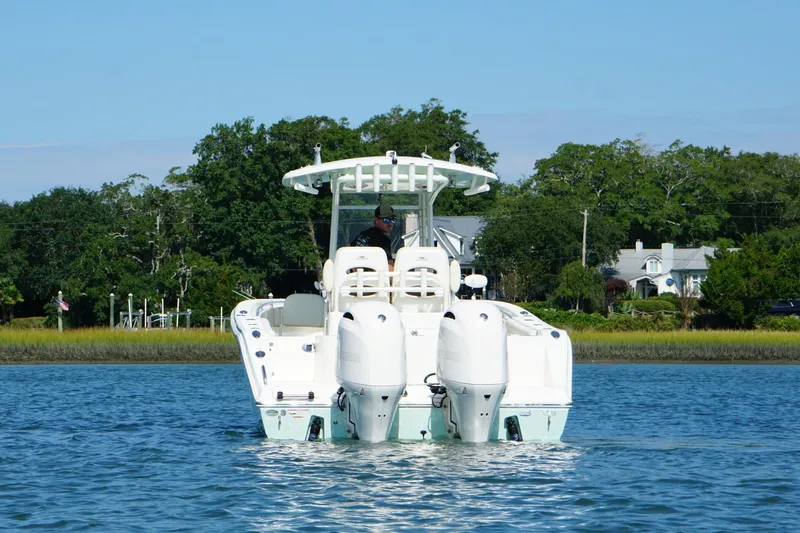 Slide: The Image of 2020 Cobia 280 Center Console boat on calm water, surrounded by lush greenery. - 25