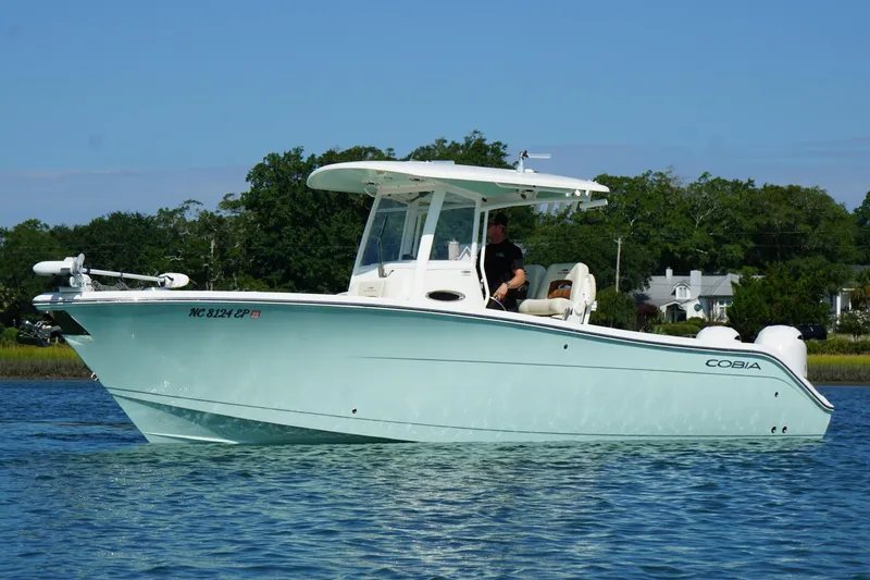 Slide: The Image of 2020 Cobia 280 Center Console boat on calm water, with trees in the background. - 29