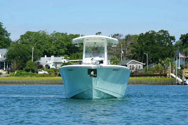 Slide: The Image of 2020 Cobia 280 Center Console boat cruising on a calm river near residential area. - 3