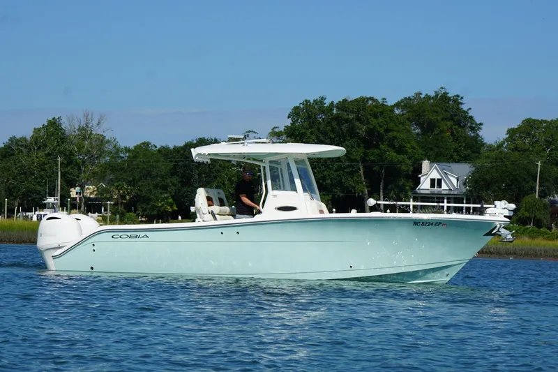 Slide: The Image of 2020 Cobia 280 Center Console boat cruising on a calm lake with trees in the background. - 30