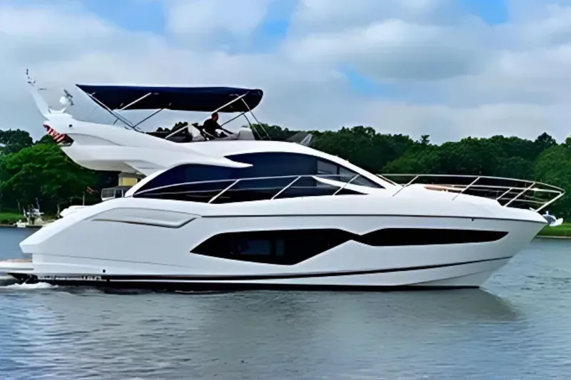 Slide: The Image of 2018 Sunseeker Manhattan 52 yacht cruising on a serene lake with lush greenery. - 0