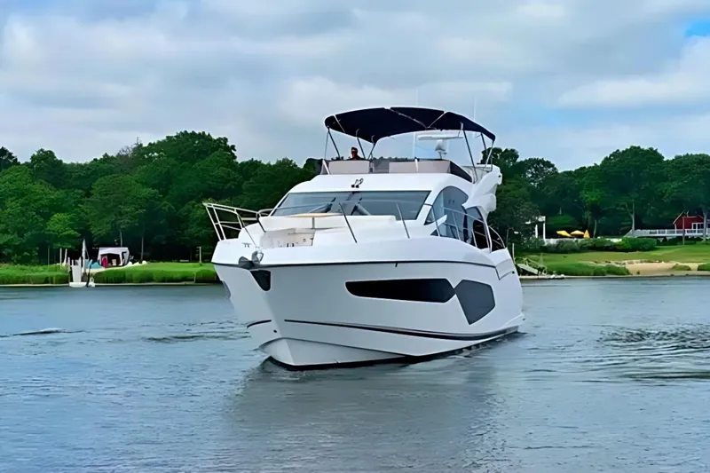 Slide: The Image of 2018 Sunseeker Manhattan 52 yacht cruising on a serene river with lush greenery. - 3