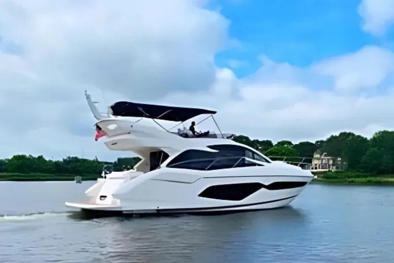 Slide: The Image of 2018 Sunseeker Manhattan 52 yacht cruising on a serene lake under a blue sky. - 5