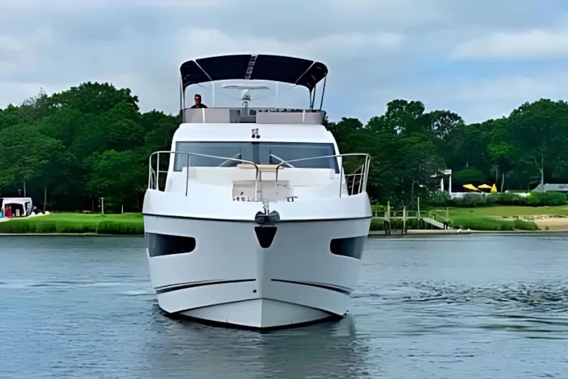 Slide: The Image of 2018 Sunseeker Manhattan 52 yacht on calm water, surrounded by lush greenery. - 6
