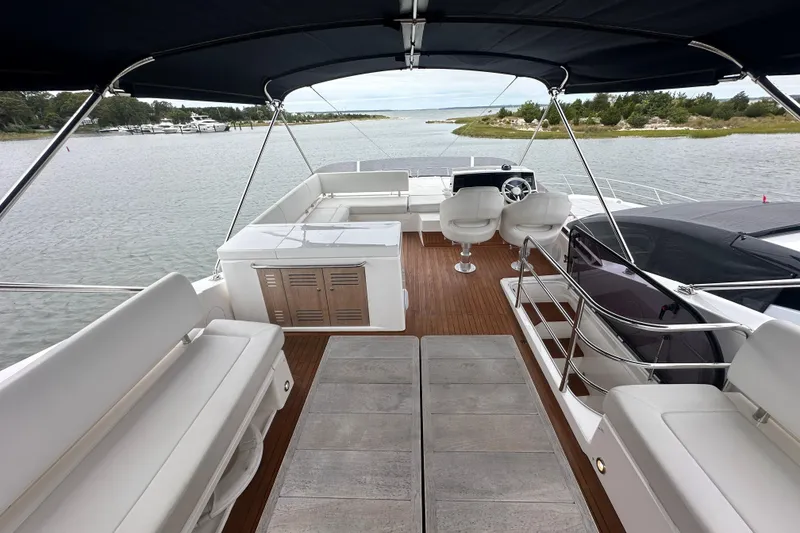 Slide: The Image of Luxurious 2018 Sunseeker Manhattan 52 yacht interior with elegant seating and helm, docked by serene waters. - 72