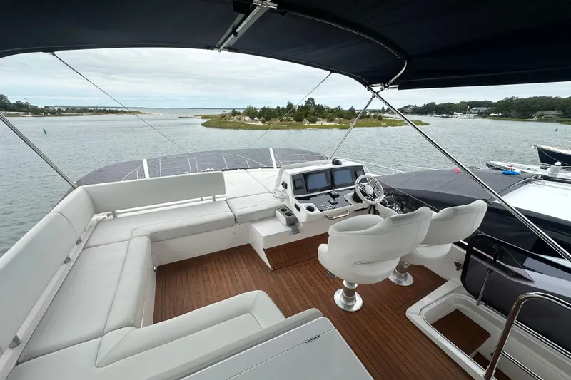 Slide: The Image of Flybridge of 2018 Sunseeker Manhattan 52 yacht with seating and helm, overlooking serene waters. - 74