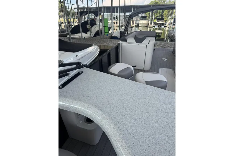 Slide: The Image of 2021 Avalon LSZ Entertainer 24' boat interior with seating and table in marina setting. - 3