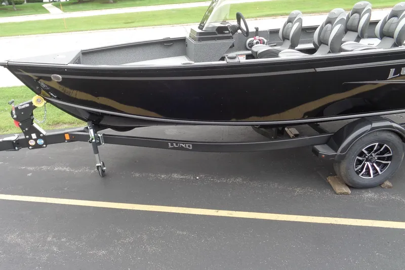 Slide: The Image of 2026 Lund 1800 Explorer SS boat on trailer, black exterior, parked on asphalt. - 3