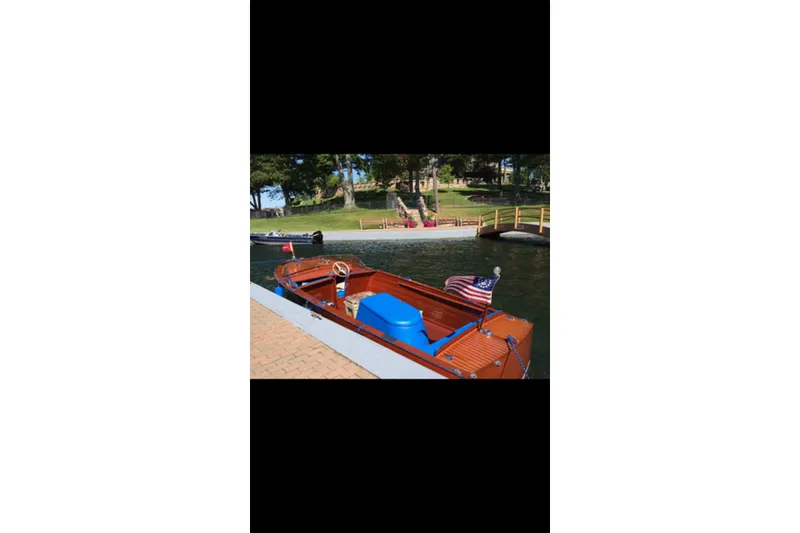 Slide: The Image of 1946 Chris-Craft U-22 Sportsman boat docked by a lakeside with American flag. - 10