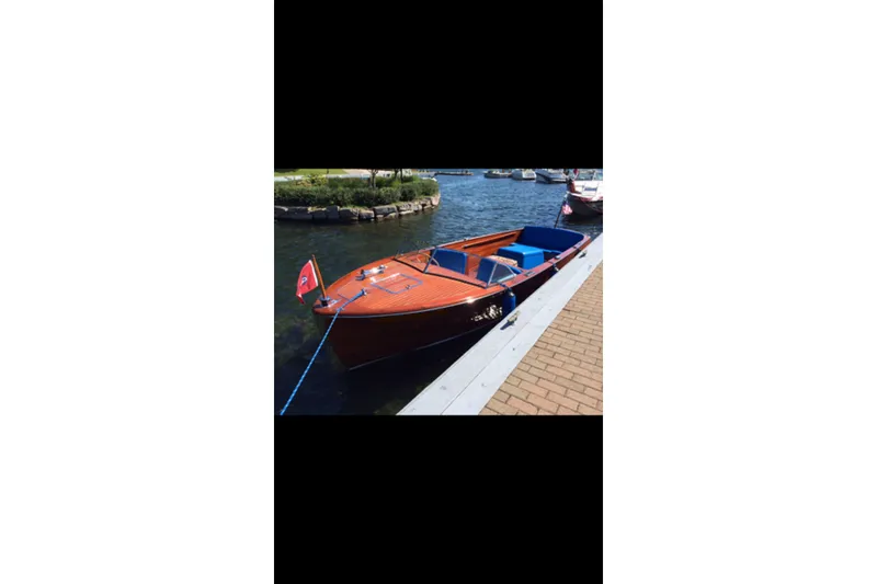 Slide: The Image of 1946 Chris-Craft U-22 Sportsman boat docked by the water, featuring classic wooden design. - 11