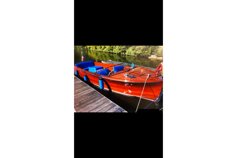 Slide: The Image of 1946 Chris-Craft U-22 Sportsman boat with vibrant wood finish docked by a serene river. - 8