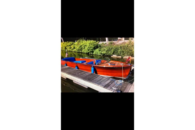 Slide: The Image of 1946 Chris-Craft U-22 Sportsman boat docked by a wooden pier, surrounded by greenery. - 9