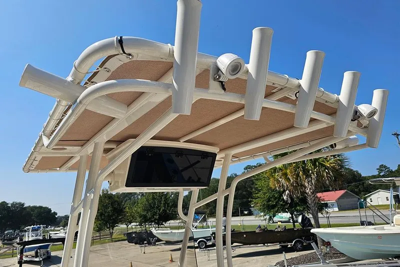 Slide: The Image of 2026 Pioneer 202 Islander boat T-top with rod holders and electronics, under clear blue sky. - 20