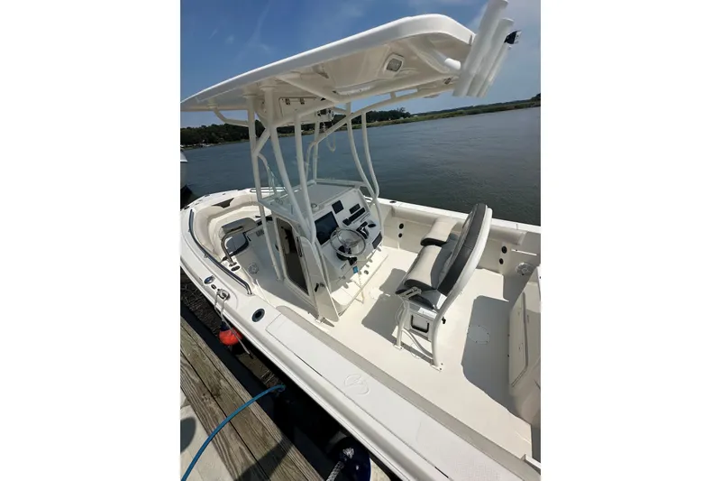 Slide: The Image of 2022 Sailfish 220 CC boat with center console and seating, docked by the water. - 34