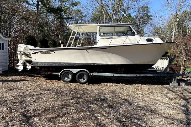 The Image of 2005 Maycraft 2700 Pilothouse boat on trailer, parked outdoors in wooded area. - 1