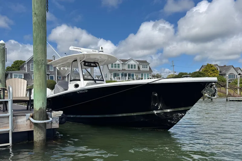Slide: The Image of 2023 Regulator 34 Center Console boat docked by waterfront homes under a blue sky. - 10
