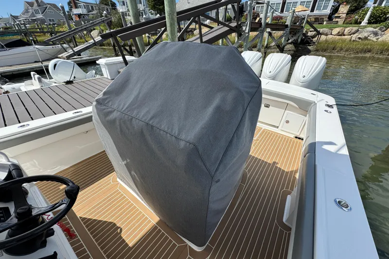 Slide: The Image of 2023 Regulator 34 Center Console boat with covered helm, docked by waterfront homes. - 100